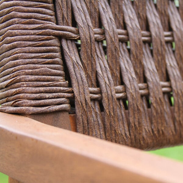 A close-up view of brown woven wicker material attached to a wooden frame, likely part of a chair.