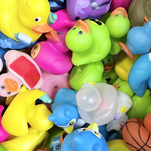 A pile of colorful rubber duck toys in various shapes and colors, closely packed together.