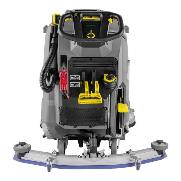 A rear view of a large, industrial walk-behind floor scrubber with a control panel, hose, and various yellow and red components visible.