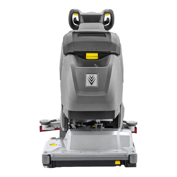 A gray and black walk-behind floor scrubber with a handle, control panel, and visible cylindrical cleaning head at the base.