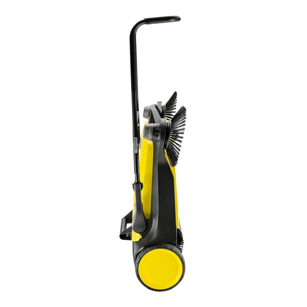 A side view of a yellow and black manual sweeper with visible rotating brushes and a handle.