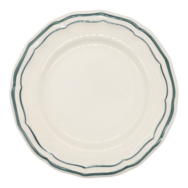 A round, white plate with scalloped edges and two green lines along the rim.