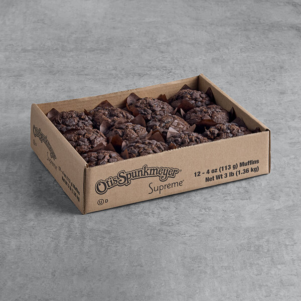A cardboard box containing twelve chocolate muffins arranged in three rows.