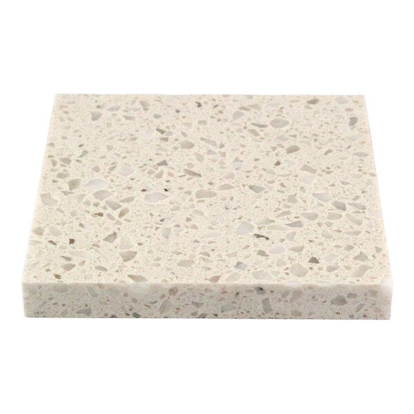 A close-up of a square, light-colored, speckled surface sample with a polished finish.