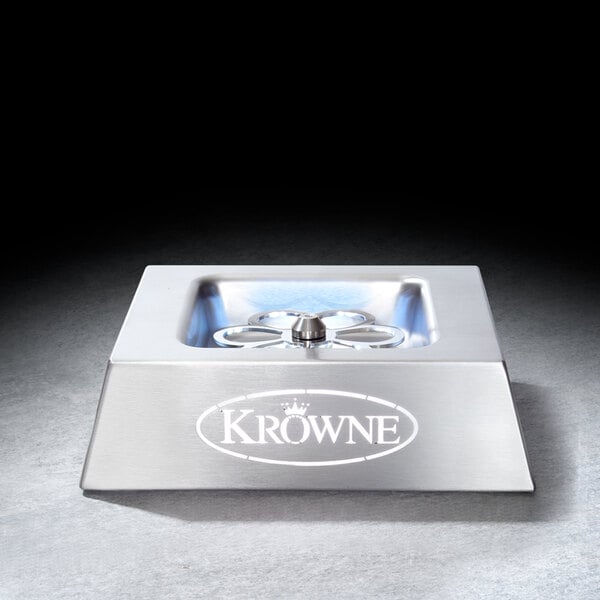 A stainless steel, low-profile tabletop device with a central circular component and the brand name 'Krowne' displayed on the front.