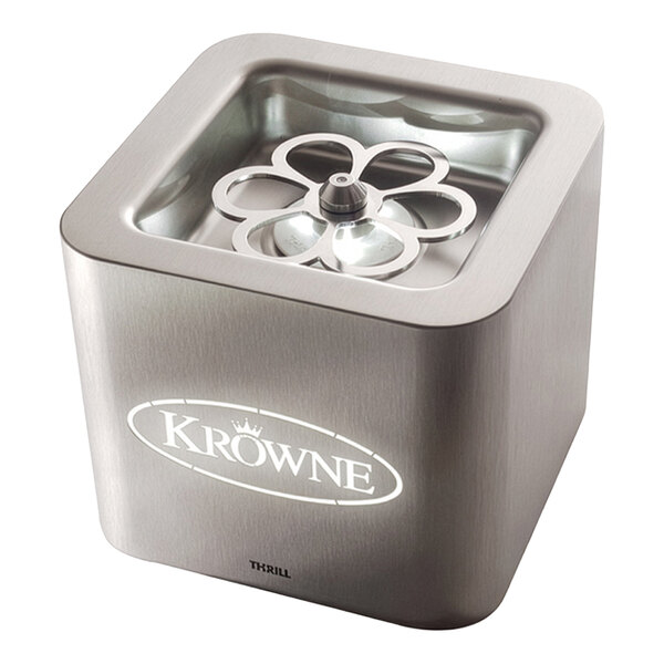 A stainless steel, cube-shaped tabletop device with a glass or plastic top, featuring a flower-shaped metal component inside and illuminated branding on the front.