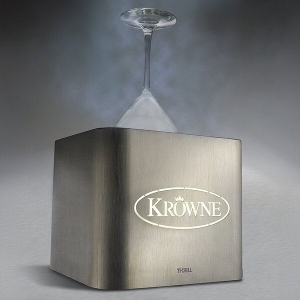 A stainless steel tabletop device emitting vapor, with an inverted wine glass placed on top and the brand name 'Krowne' illuminated on the front.
