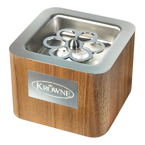 A square, wood-finish tabletop device with a stainless steel top and a flower-shaped metal component in the center, featuring a Krowne logo on the front.