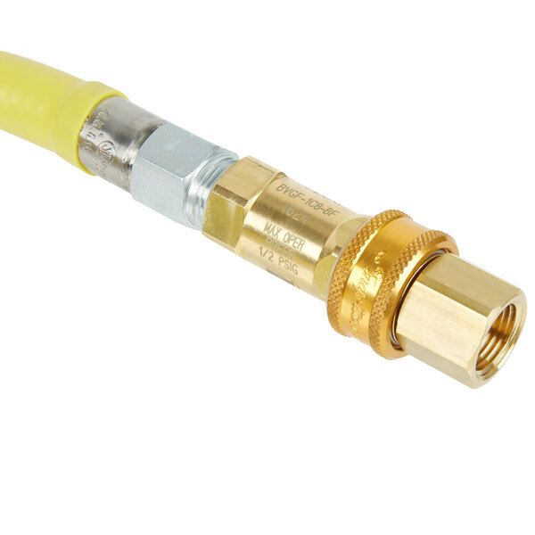 A close-up of a yellow T&S gas connector hose with brass and silver connectors.