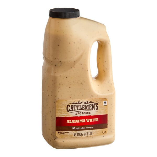 A large plastic jug with a handle, filled with a creamy, speckled white sauce and labeled 'Cattlemen's BBQ Sauce Alabama White.'