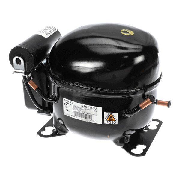 A black, dome-shaped mechanical component with copper pipes and a label, likely a refrigeration compressor.