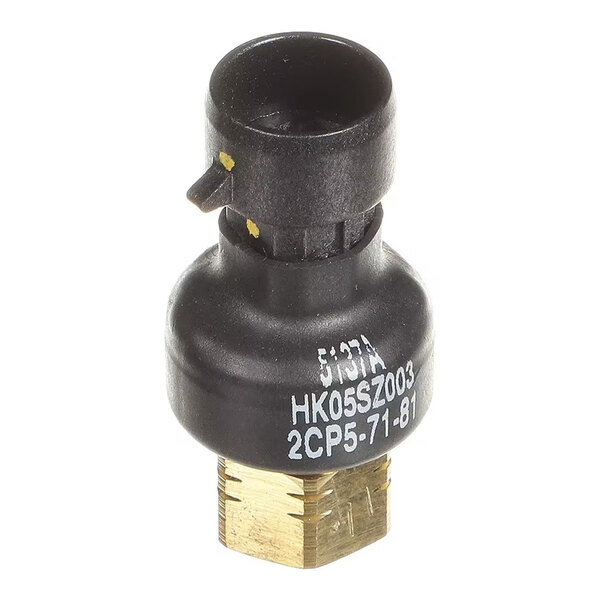 A small cylindrical electronic component with a black plastic top and a brass hexagonal base, featuring white printed text on its side.