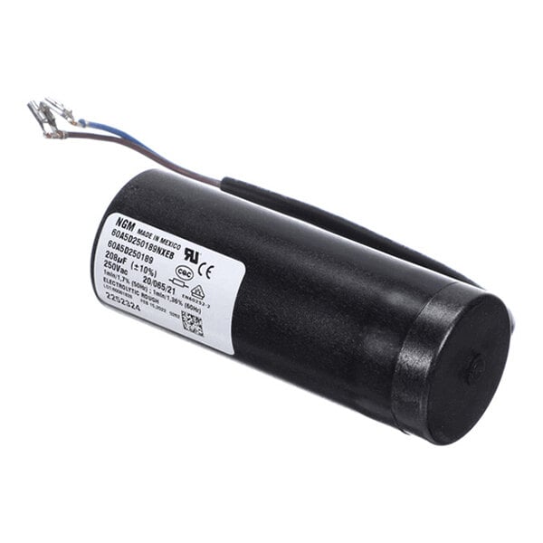 A cylindrical black electronic component with attached wires and a white label displaying technical specifications.