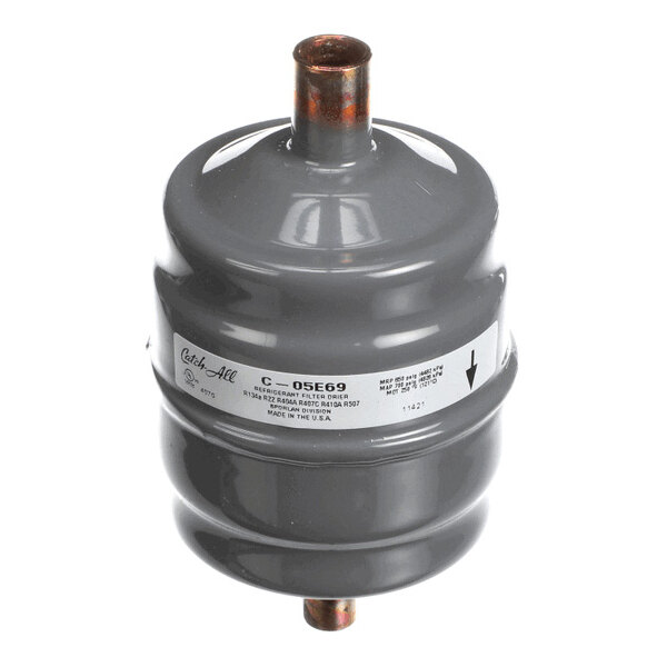 A cylindrical metallic component with two copper pipe connections and a label wrapped around its body.
