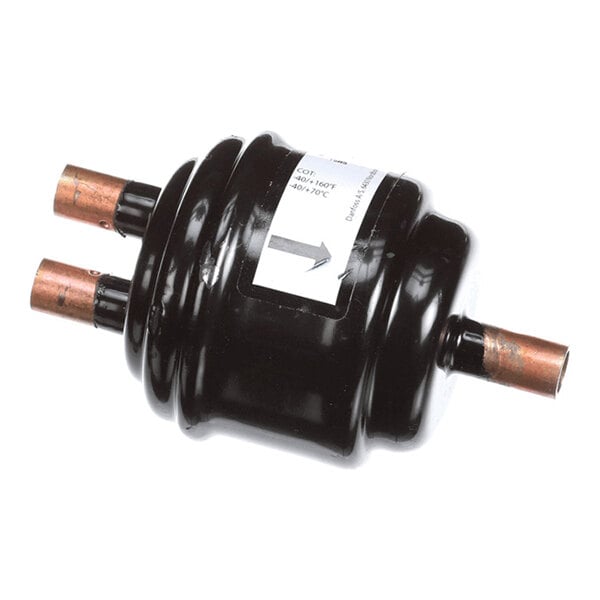 A black cylindrical component with copper pipe fittings on both ends and a label with an arrow indicating flow direction.