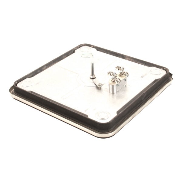 A square metallic plate with a black border, featuring a central bolt and a small metal component with screws attached.