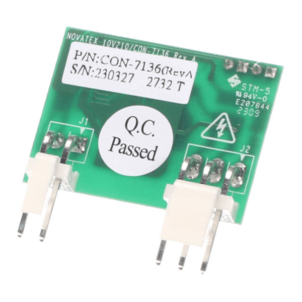 A small green circuit board with two white connectors, several metal pins, and labels including a 'Q.C. Passed' sticker.
