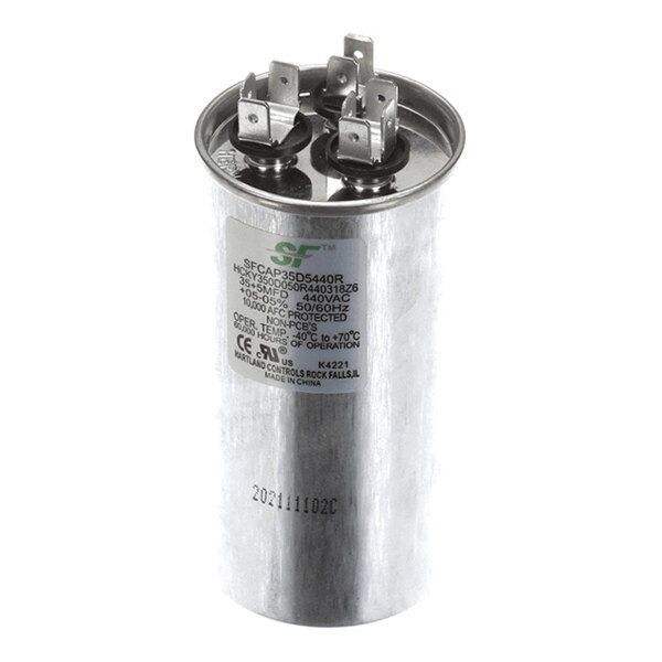 A cylindrical metal capacitor with three electrical terminals on top and a label displaying technical specifications.