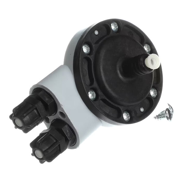 A close-up view of a mechanical component with a round black top secured by screws, two cylindrical connectors, and a loose screw nearby.