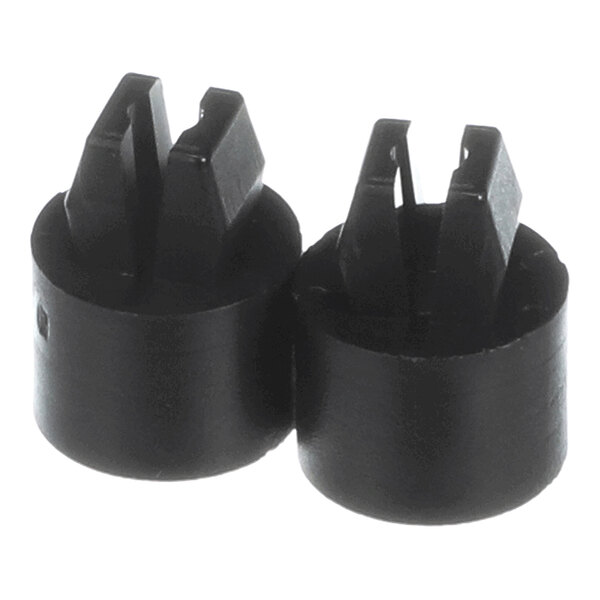 Two black cylindrical objects with slotted, raised sections on top, resembling plastic or rubber grommets.