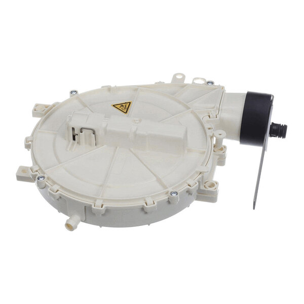 A round, beige plastic mechanical component with a black cylindrical attachment and several screws, featuring a warning symbol on its surface.