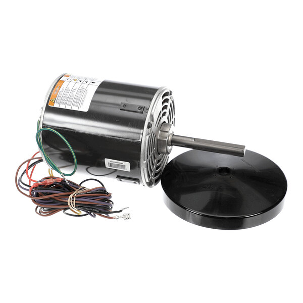 An electric motor with a cylindrical black housing, a protruding metal shaft, a bundle of multicolored wires, and a separate round black cover placed beside it.