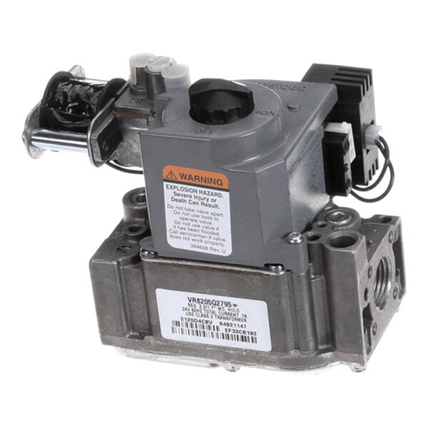 A metallic gas valve assembly with a warning label, adjustment knob, and multiple connection points.
