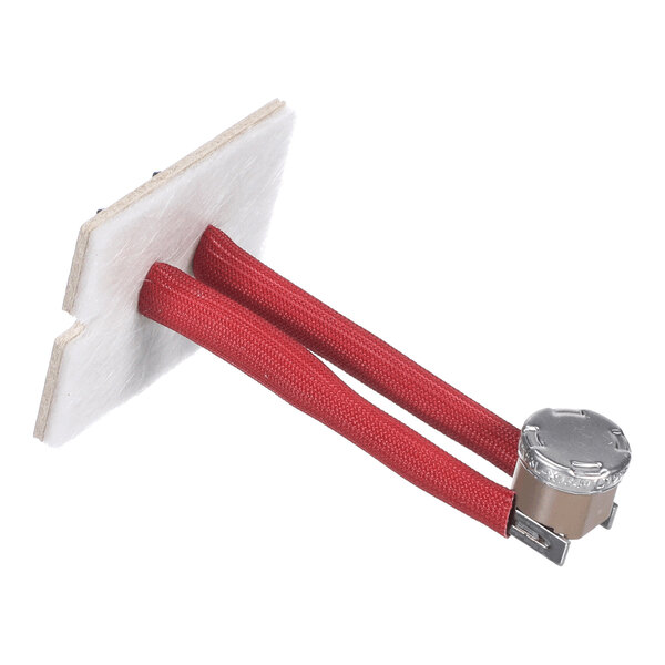 A small electronic component with two red insulated wires attached to a metal cylindrical part, mounted on a rectangular white board.