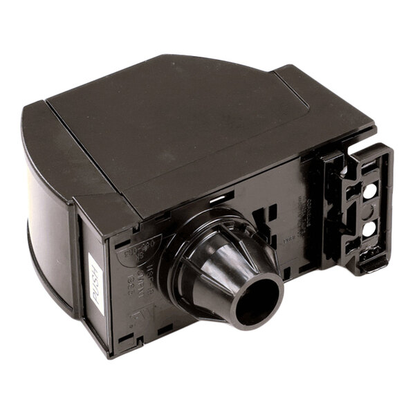 A black plastic valve component with a cylindrical nozzle and a push button, featuring mounting brackets on one side.