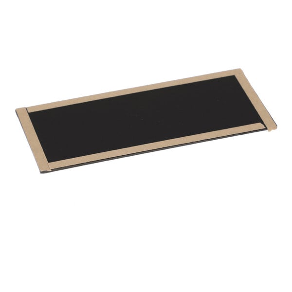 A rectangular black object with a gold border, lying flat on a white surface.