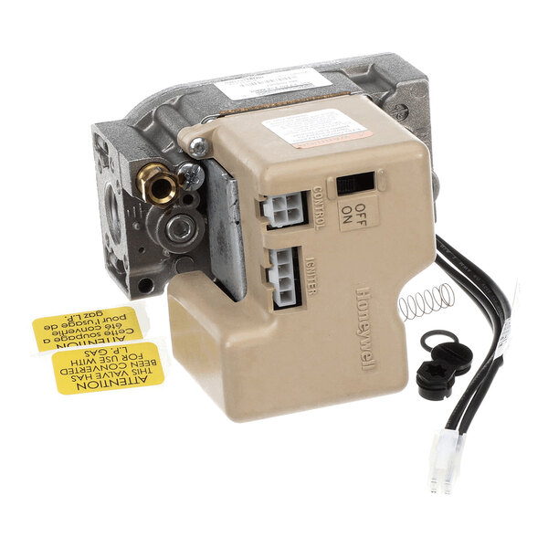 A mechanical component with a beige plastic cover, metal fittings, electrical connectors, a black cable, and several loose parts including a spring and rubber grommets.