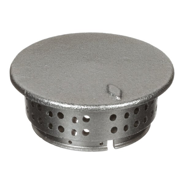 A round metallic object with a solid top and perforated sides, featuring multiple circular holes and a small notch at the bottom edge.