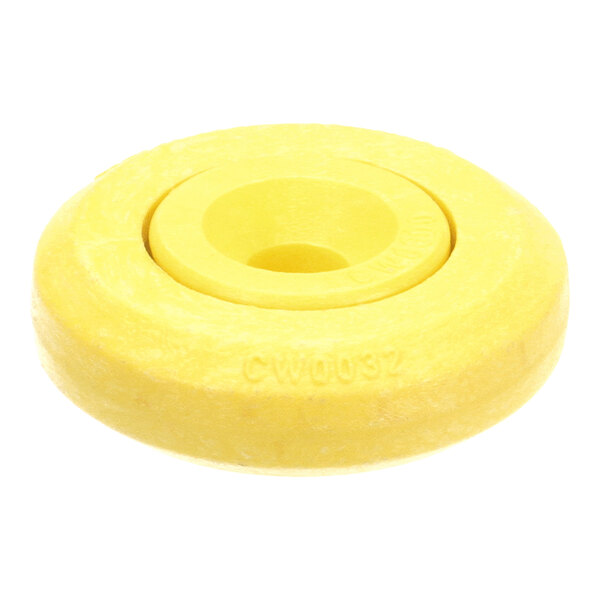 A yellow, round, solid object with a central hole, resembling a wheel or roller, with some text engraved on its side.