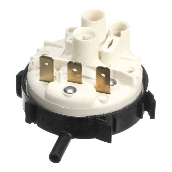 A round plastic component with three metal prongs, two screws, and several cylindrical ports, likely an electrical or mechanical switch.