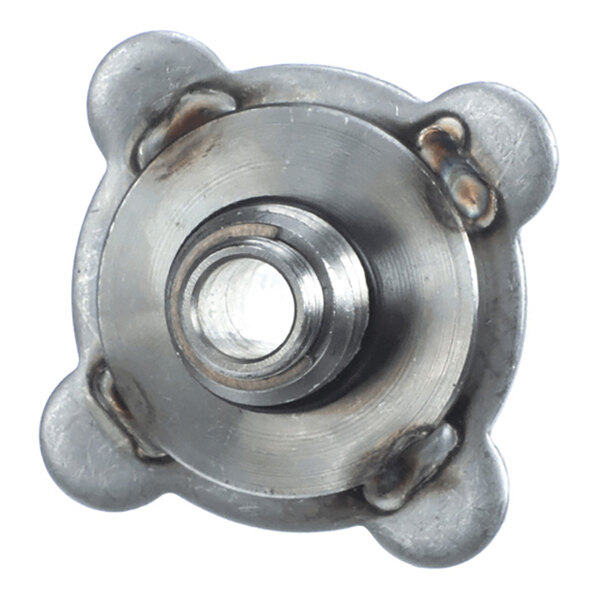 A close-up view of a metallic, circular mechanical component with a central hole and four rounded protrusions, showing signs of welding at the joints.