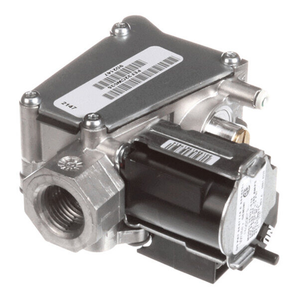 A metallic mechanical component with threaded ports, a black rectangular section, and several labels with barcodes.