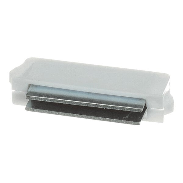 A small rectangular component with a white plastic casing and a visible metal piece, likely a magnet, partially exposed on one side.