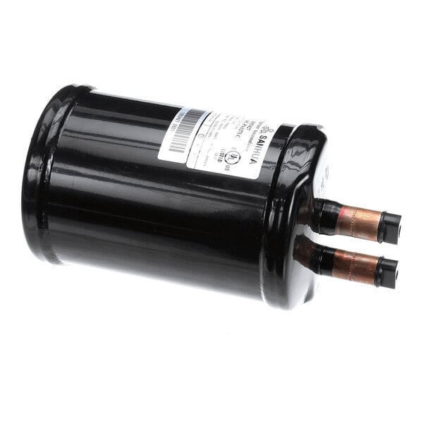 A cylindrical black metal component with two copper pipe fittings and a label attached to its side.