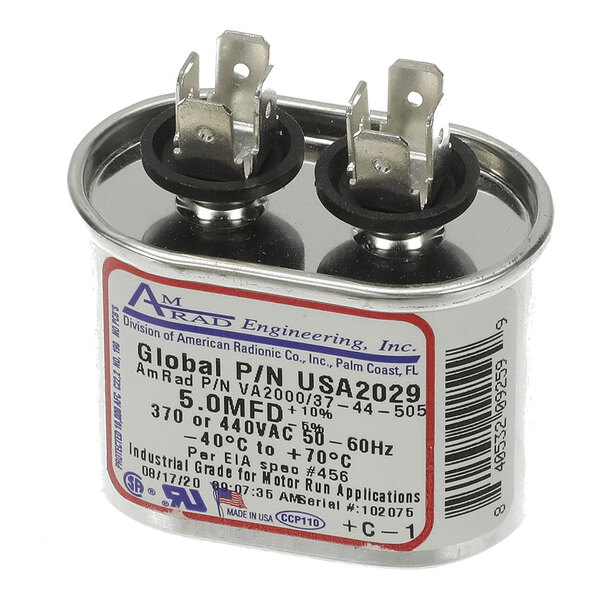 A metal oval-shaped capacitor with two sets of electrical terminals on top and a label indicating specifications such as 5.0 MFD, 370 or 440 VAC, and temperature ratings.
