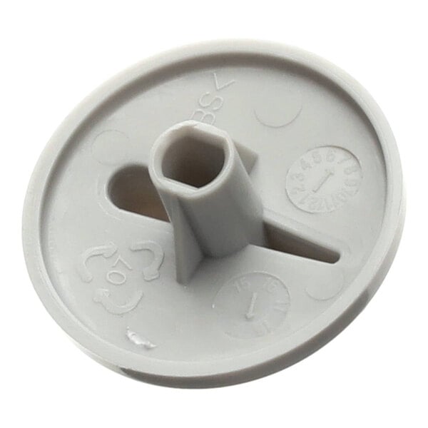 A round, gray plastic knob with a central hexagonal hole and a slotted opening, featuring molded markings and symbols on its surface.