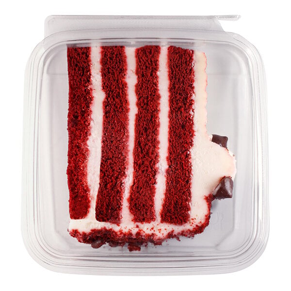 A slice of red velvet cake with cream cheese frosting is shown inside a clear plastic container.