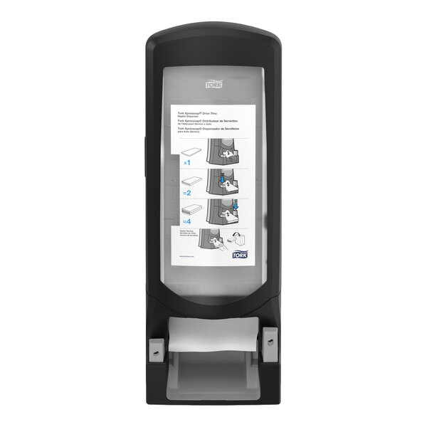 A black and gray wall-mounted dispenser with an instructional diagram displayed on the front panel.