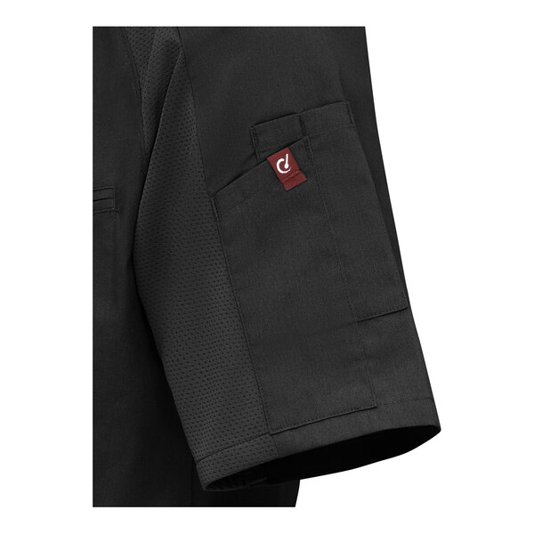 A close-up of a black short sleeve garment with a pocket and a small red tag on the sleeve.