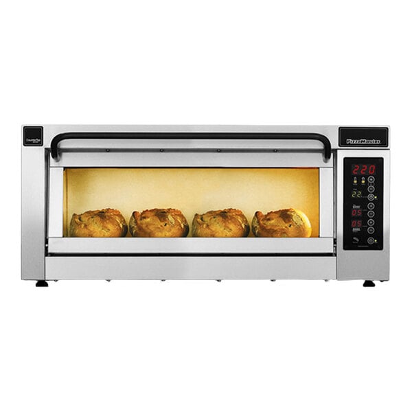 A stainless steel countertop oven with a glass window showing four baked items inside and a digital control panel on the right side.