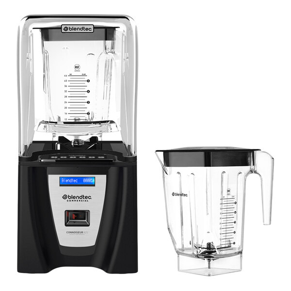 A black and silver blender with a transparent sound enclosure, accompanied by an additional clear blending jar with a handle and measurement markings.