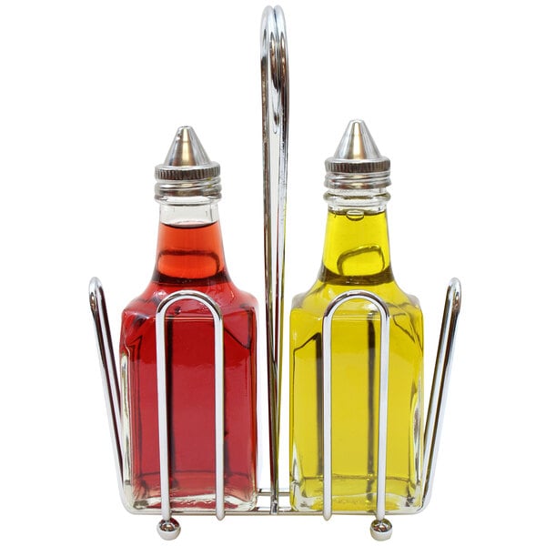 Two glass bottles, one filled with red liquid and the other with yellow liquid, are held in a chrome rack with metal pour spouts.
