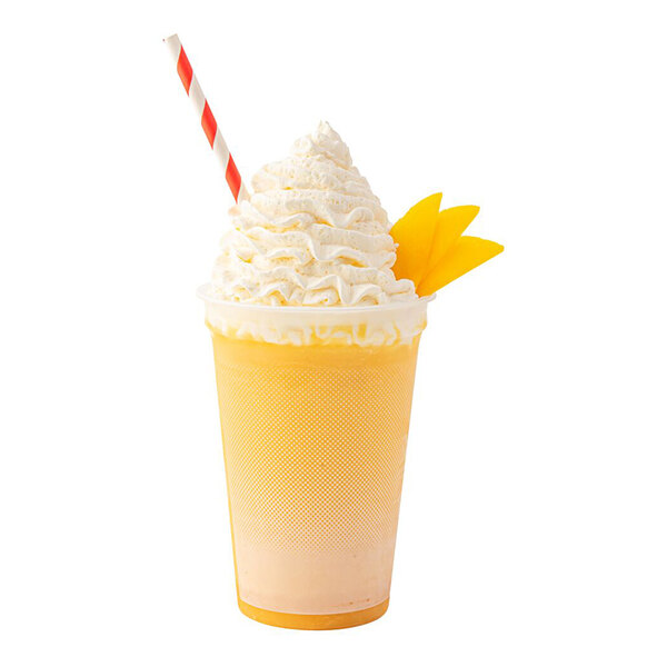 A yellow smoothie in a clear cup topped with a large swirl of whipped cream, garnished with mango slices and a red-and-white striped straw.
