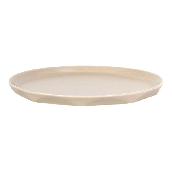 A round, beige plate with a slightly irregular, organic-shaped rim.