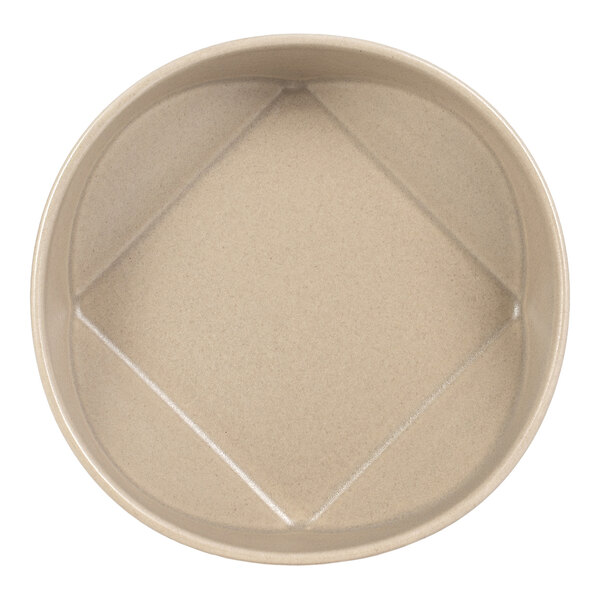 A round, beige bowl with a unique geometric pattern on the interior base.