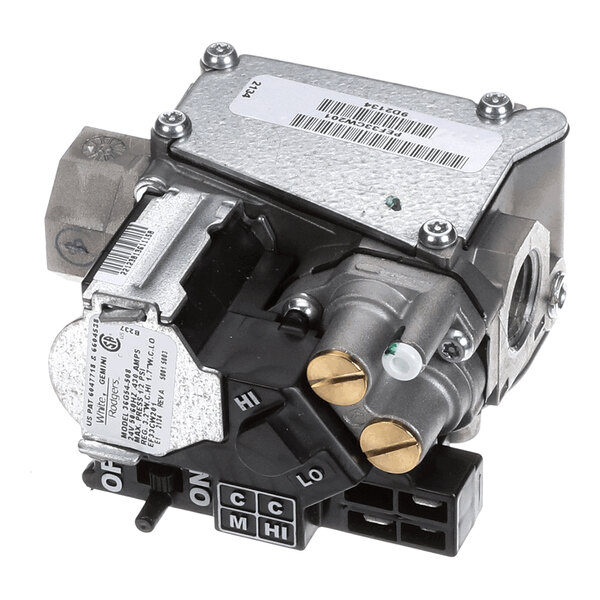 A metallic mechanical component with various knobs, switches, and connectors, featuring labels and a barcode on its surface.